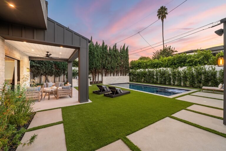 Modern backyard with pool, patio furniture, and sunset sky in a suburban setting.